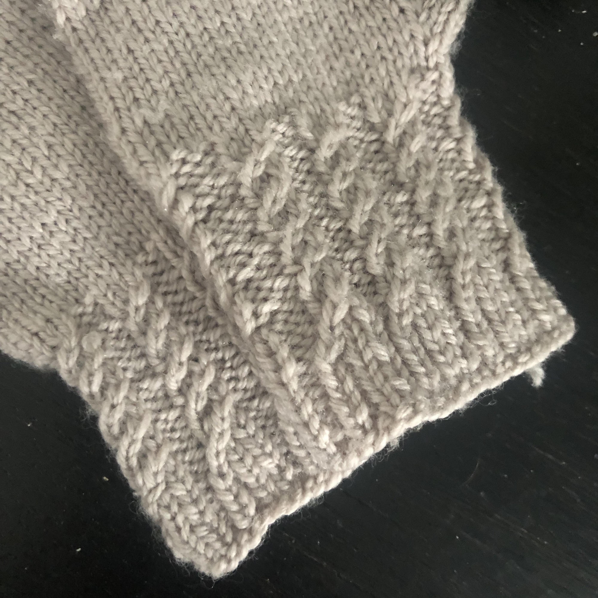 Cable knitted cuff of a pair of gloves in cream color.