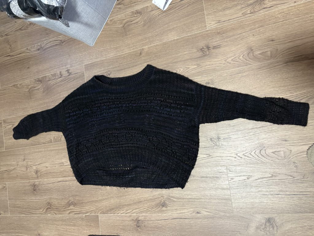 Black knitted sweater on wooden floor